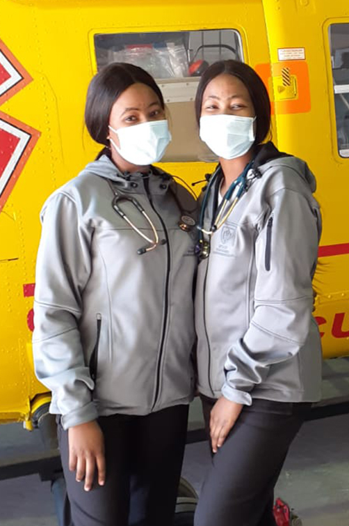 Drs Keitumetse (left) and Boitumelo (right) Molise in front of a medical rescue helicopter