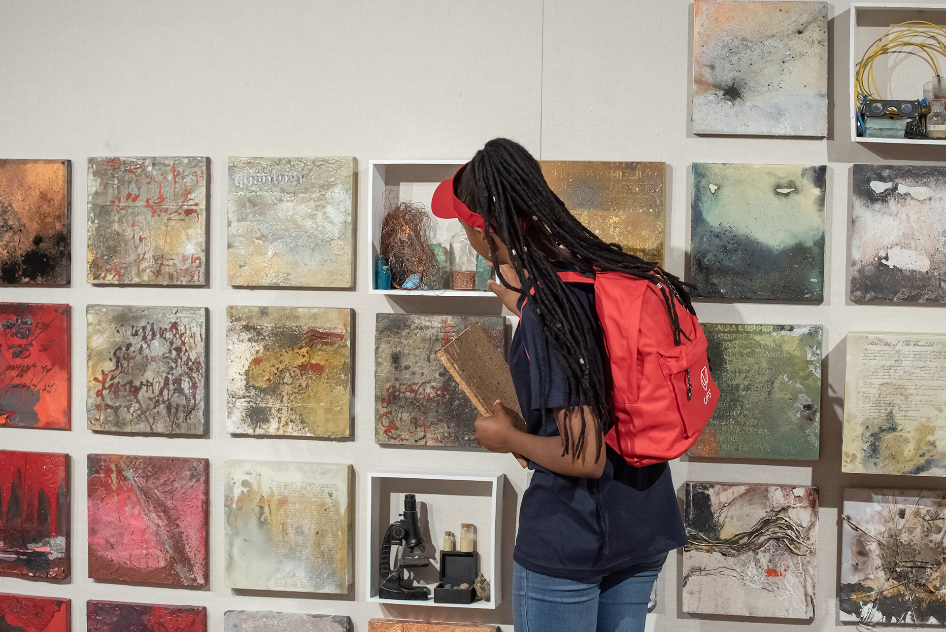 Student studying canvas art work on a wall.