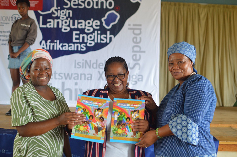 Deputy Director   - Academy for Multilingualism with the school teachers showing off the donated Dictionaries