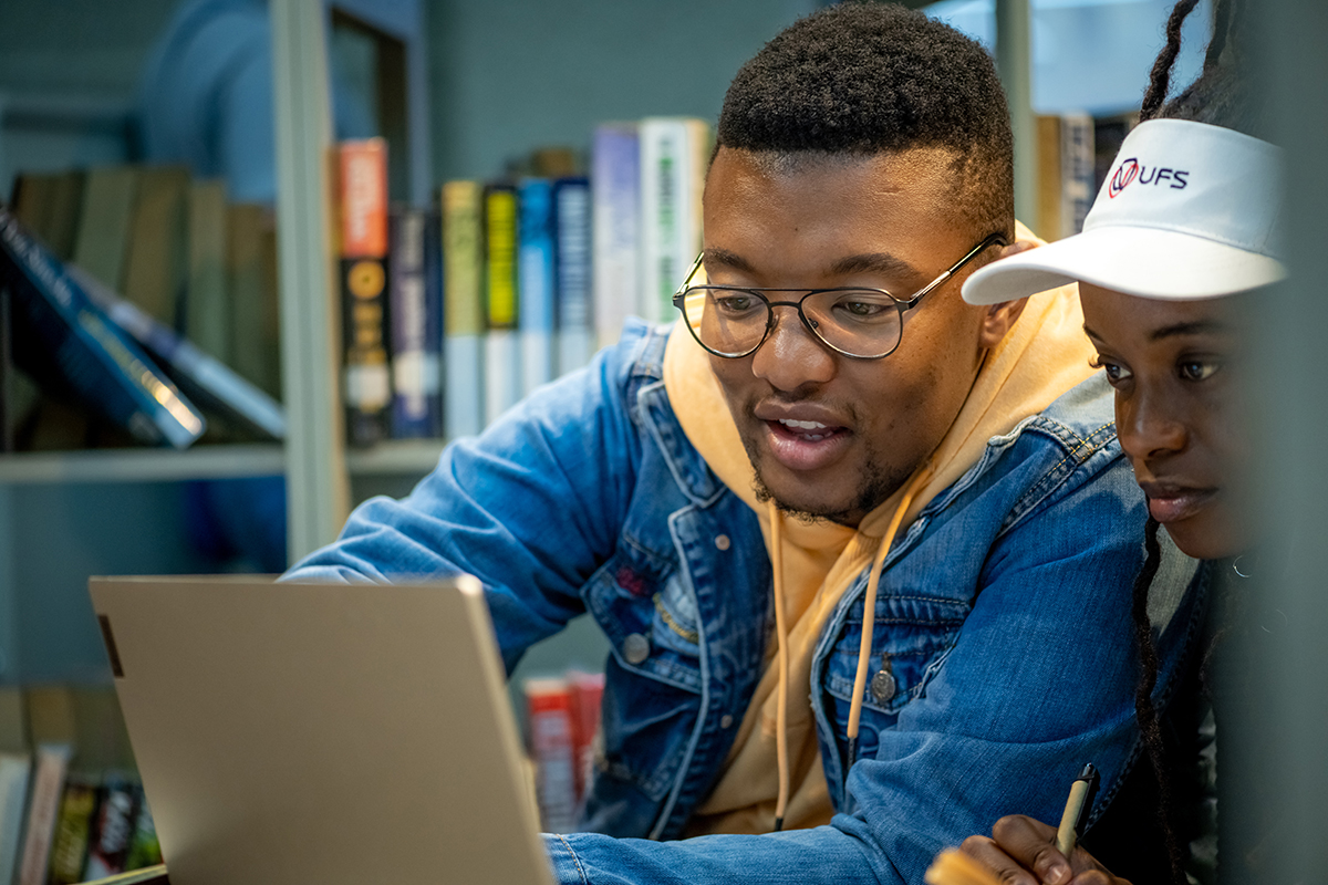 Two students studying in front of a laptop